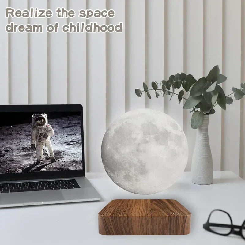 Lampe lune flottante blanche à côté d'un ordinateur