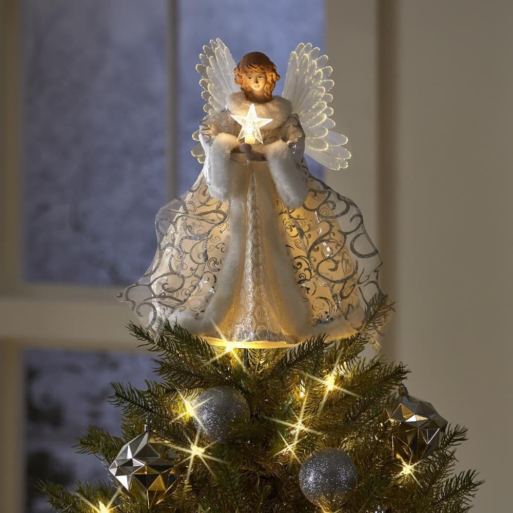 Ange lumineux posé sur la pointe d’un sapin décoré