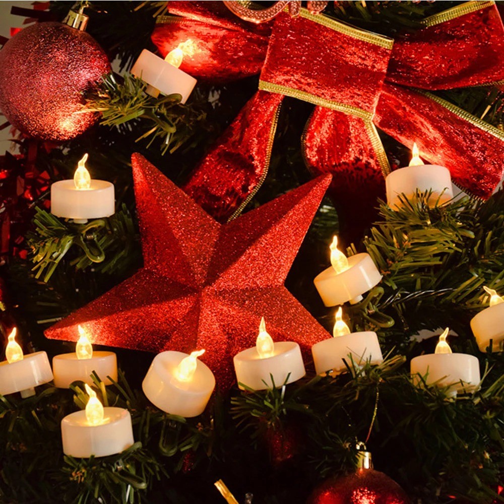 Bougies chauffe-plat LED allumées au pied d’un sapin décoré