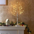 Petit bouleau lumineux blanc allumé au milieu d’une déco de Noël