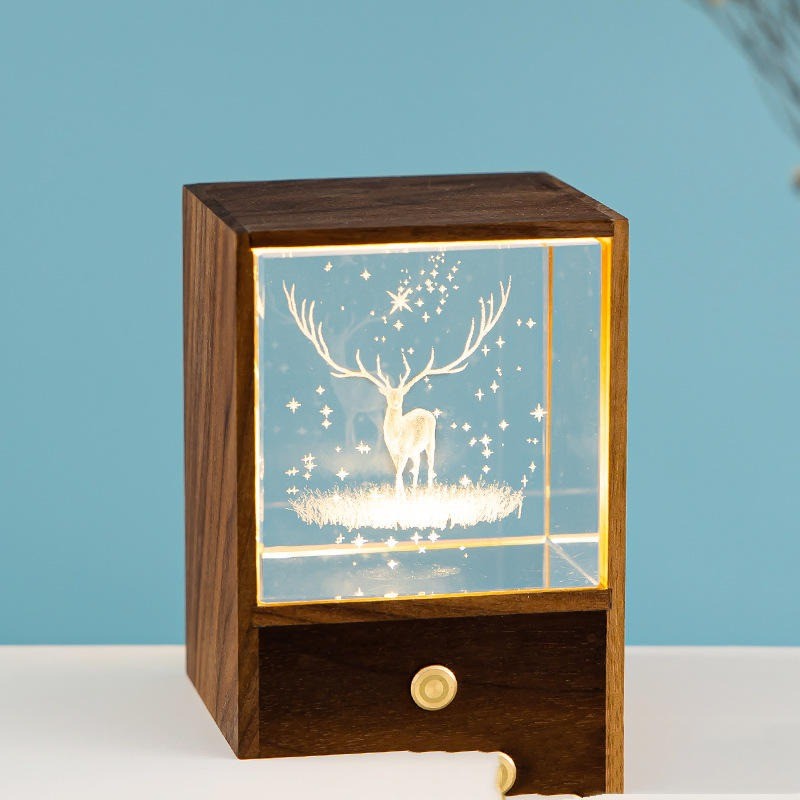 Cube de cristal gravé d’un cerf, éclairé dans son écrin en bois foncé