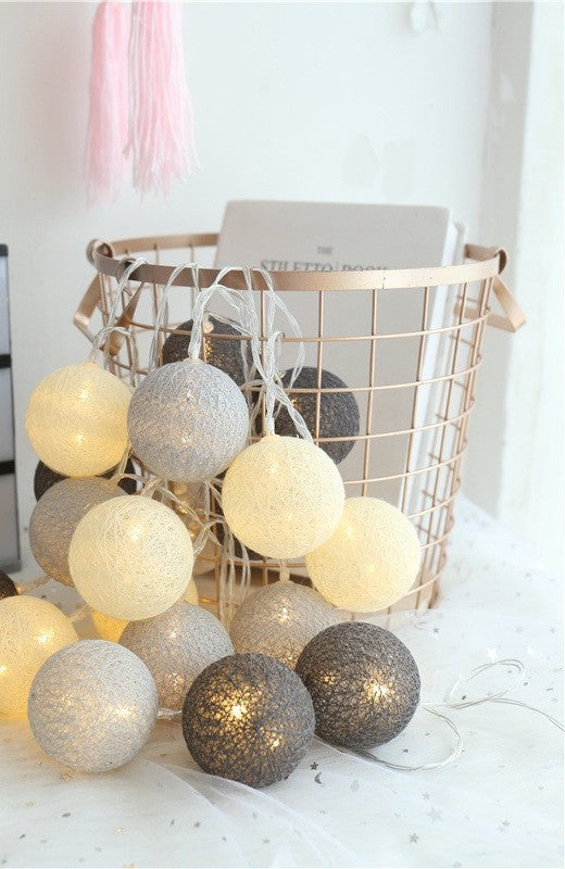 Guirlande de boules de coton grises et crème dans un panier métallique