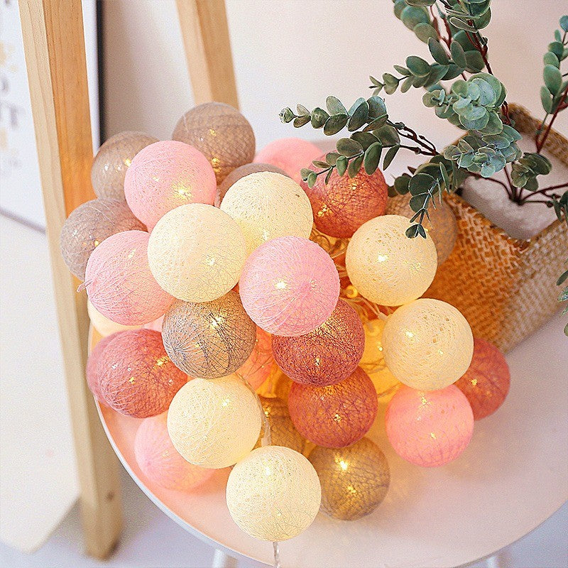 Guirlande de boules de coton roses et crème posée dans un panier