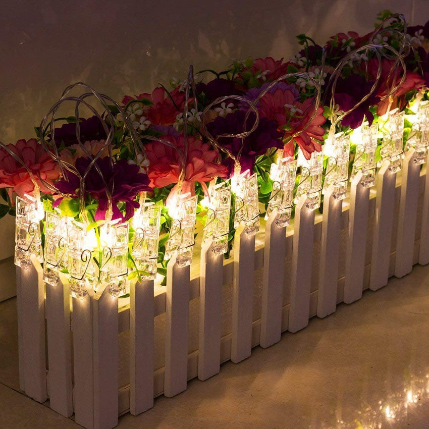 Pinces lumineuses LED blanc chaud sur une clôture fleurie