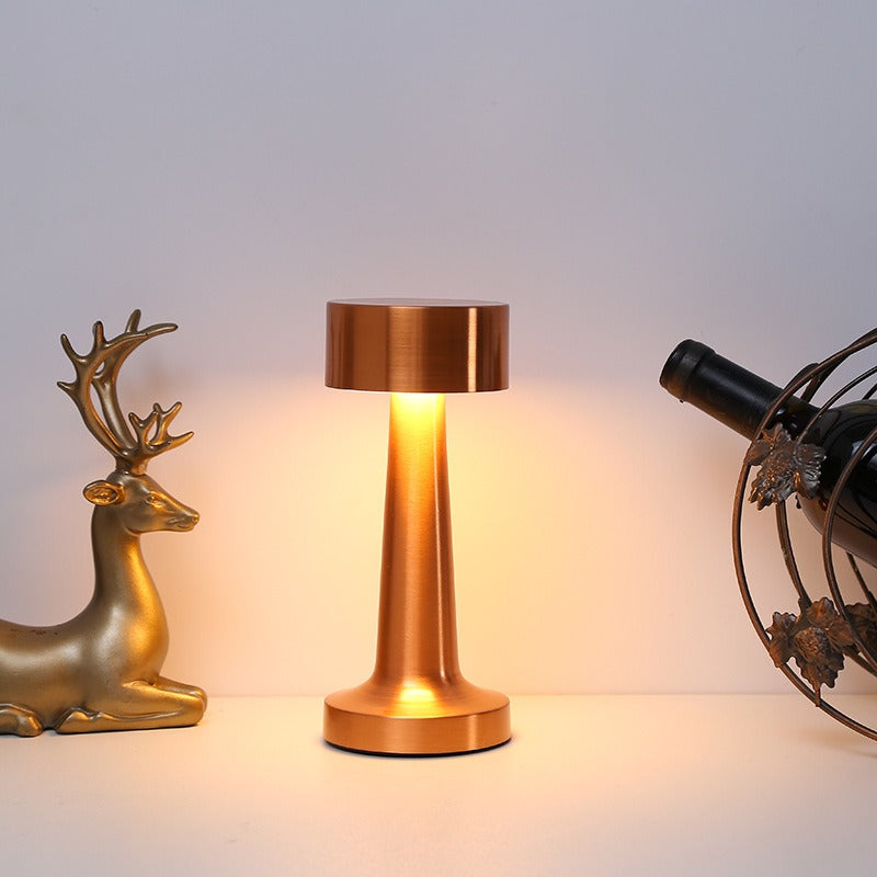 Lampe bistrot en métal allumée d’une lumière chaude sur une console