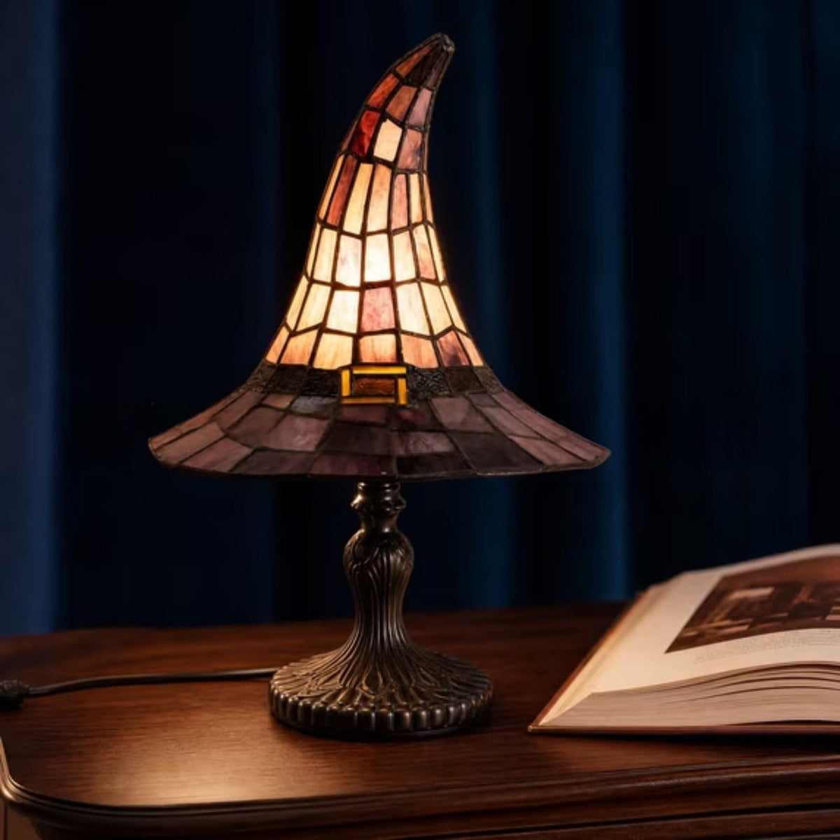 Lampe chapeau de sorcière effet vitrail ambré, allumée sur une table
