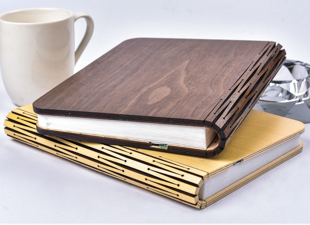 Lampe livre fermée, couverture en bois de noyer, posée sur une pile de livres