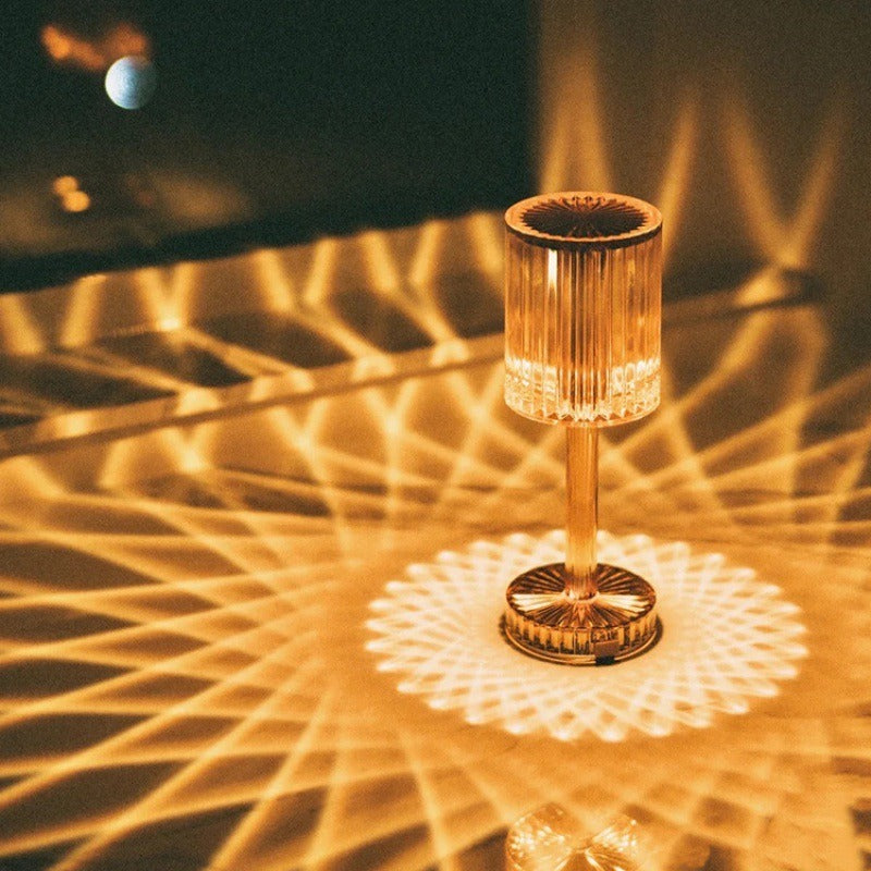Lampe cristal acrylique projetant des reflets dorés sur une table