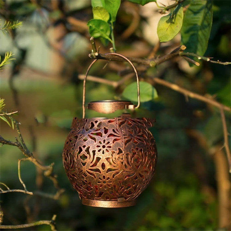 Lanterne solaire bronze ajourée suspendue dans un arbre