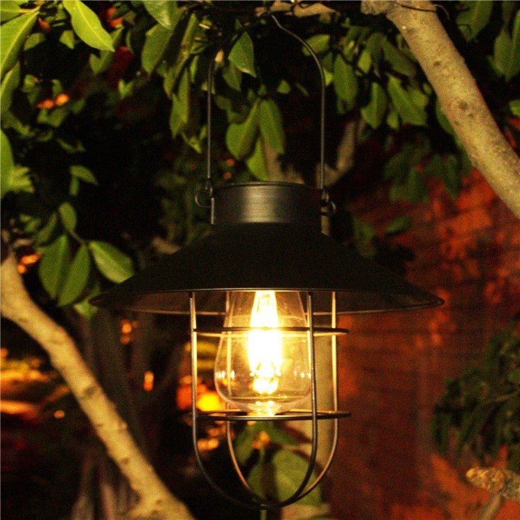 Lanterne solaire noire éclairant un jardin le soir
