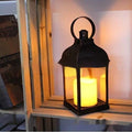 Lanterne vintage noire à la bougie LED allumée, posée près d’une fenêtre