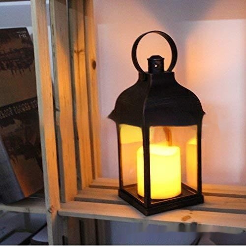 Lanterne vintage noire à la bougie LED allumée, posée près d’une fenêtre