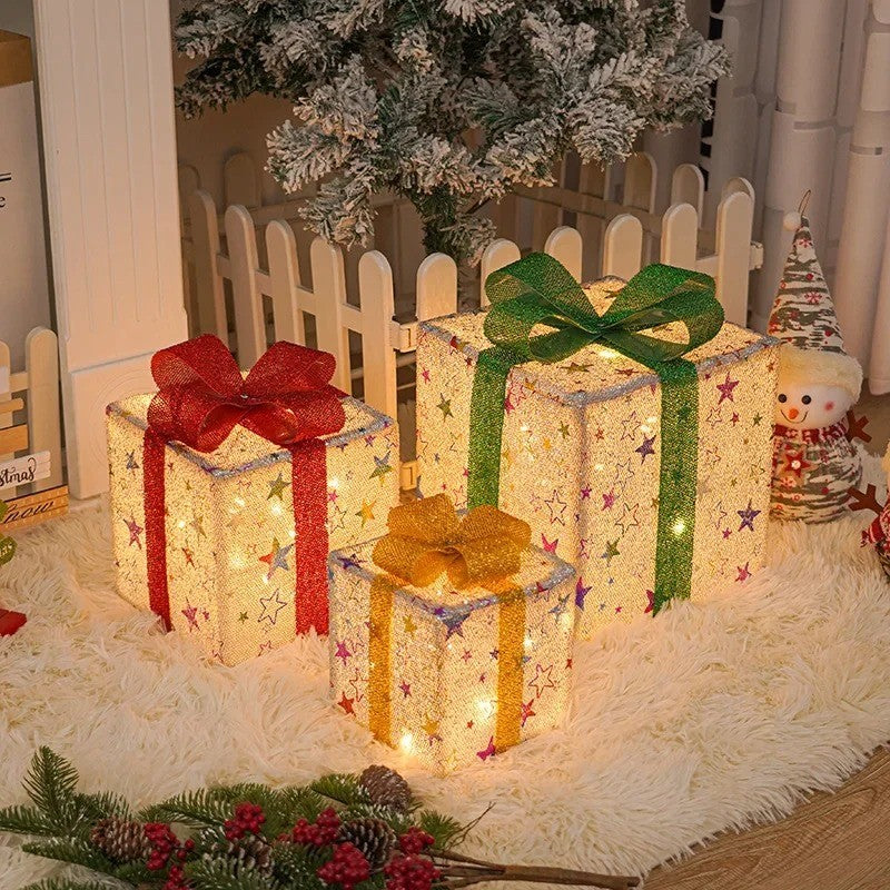 Trois paquets cadeaux lumineux à étoiles dorées et nœuds rouge, vert et or