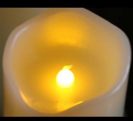 Gros plan sur la flamme LED au cœur d’une bougie en cire