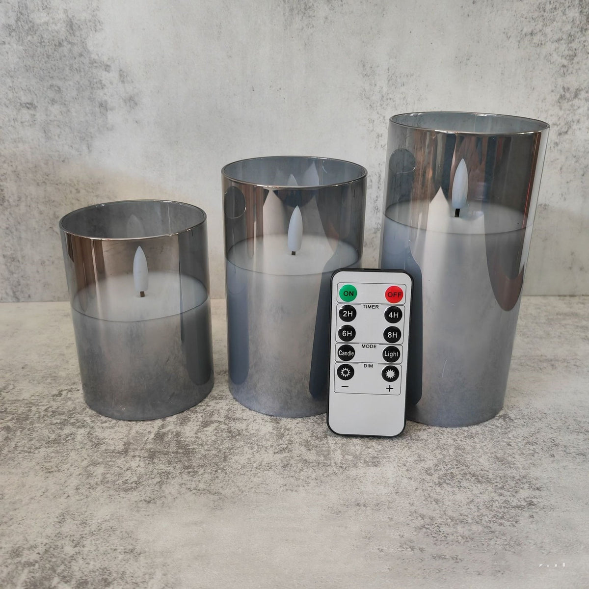Trois bougies LED dans des verres gris fumé, avec leur télécommande