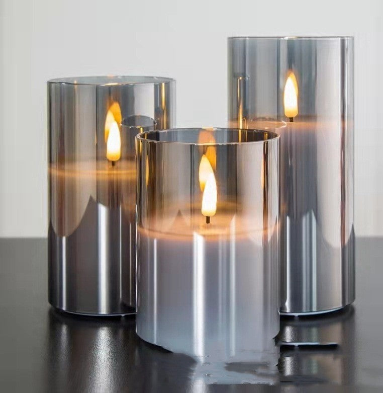 Trio de bougies LED en verre gris fumé posé sur une table sombre