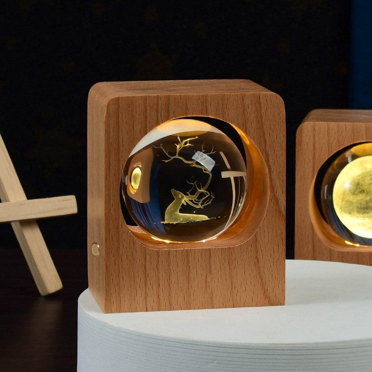 Boule de cristal gravée d’un cerf, illuminée dans un socle en hêtre