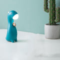 Veilleuse petit dinosaure bleu canard allumée sur un bureau