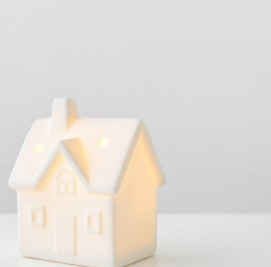 Petite maison en céramique blanche ajourée, éclairée de l’intérieur